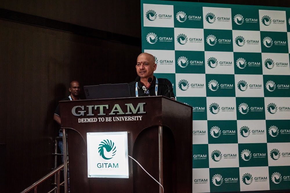 A Steering Committee member addressing the audience from the podium at GITAM University during a REEV technical session