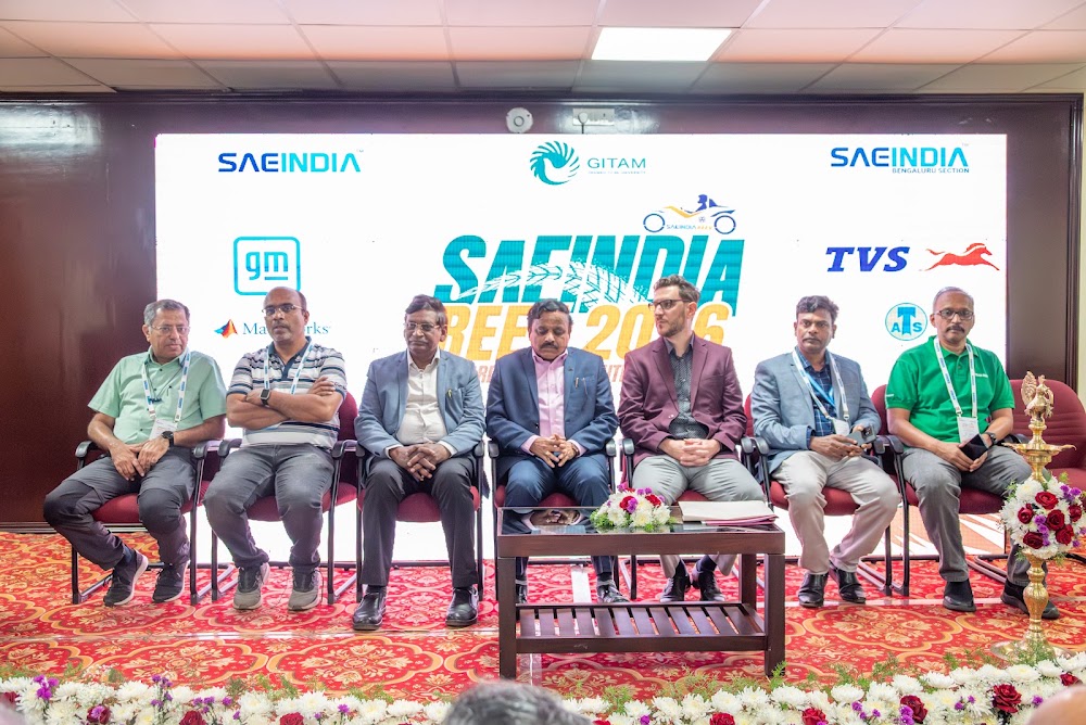 A panel of technical evaluators and industry judges seated on stage in front of the REEV SAEINDIA 2026 backdrop