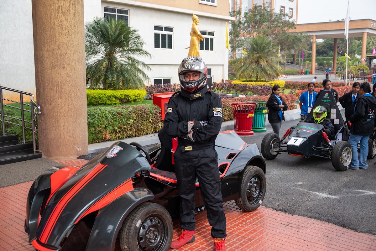 REEV driver in racing suit and helmet standing beside their vehicle before a run