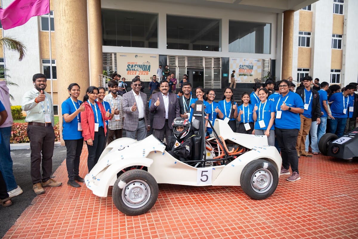 Team and officials giving a thumbs up beside their REEV vehicle outside the GITAM University venue