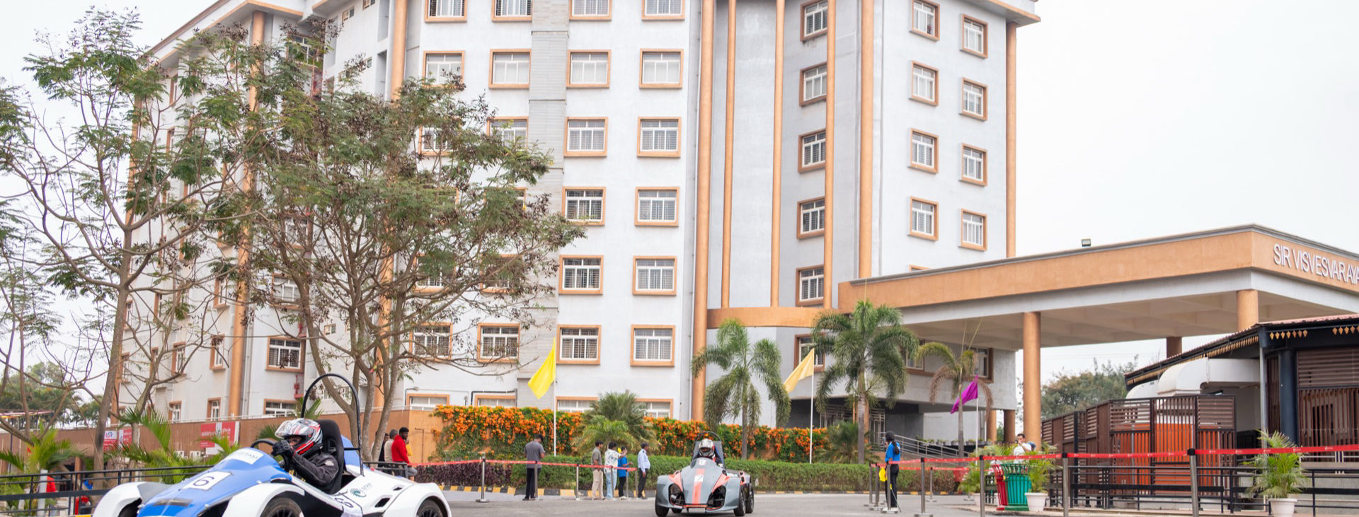 GITAM University's Bengaluru campus building, with REEV vehicles on track in the foreground